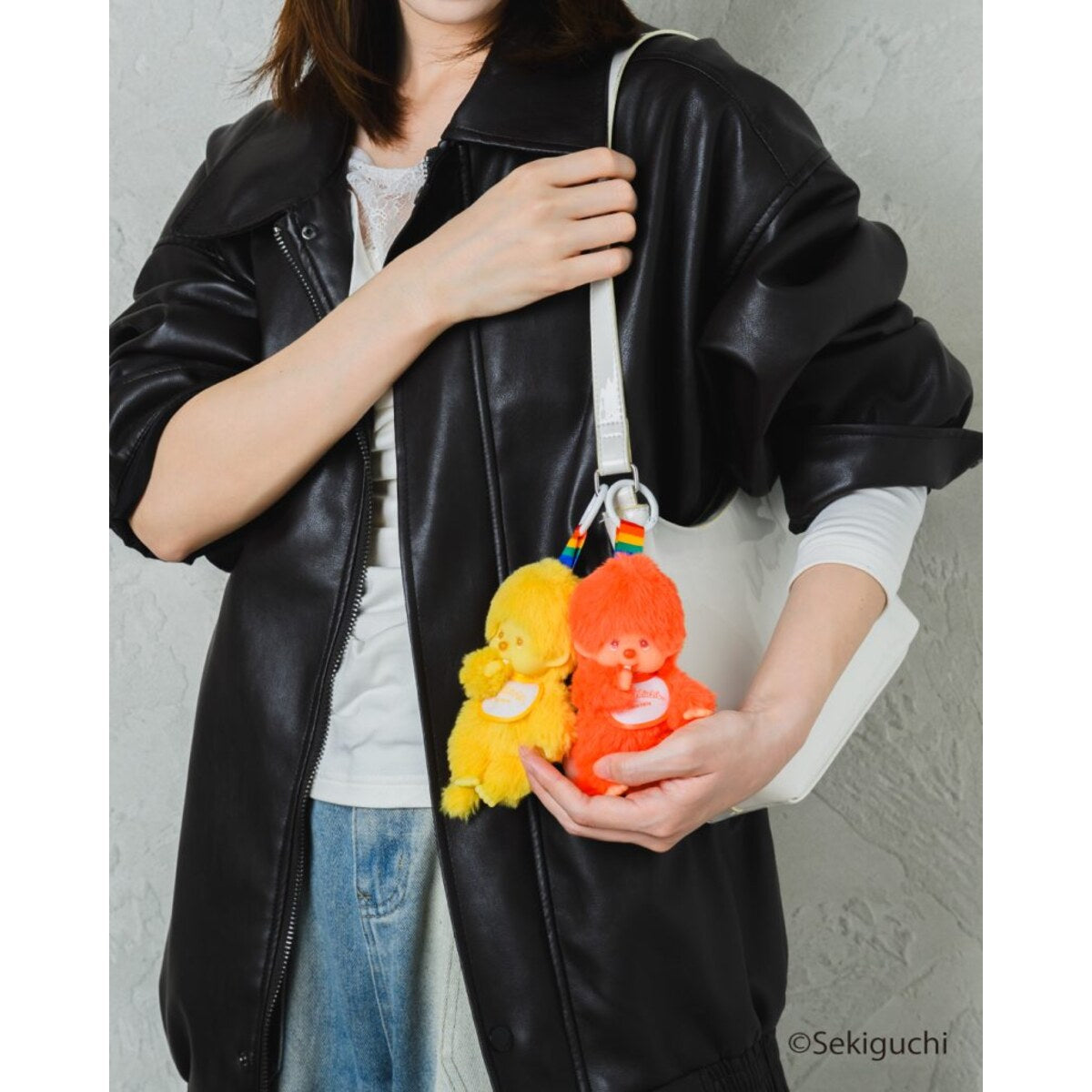 Orange and yellow macaron Monchhichi Colorful Fantasy plush keychains carried on a shoulder bag