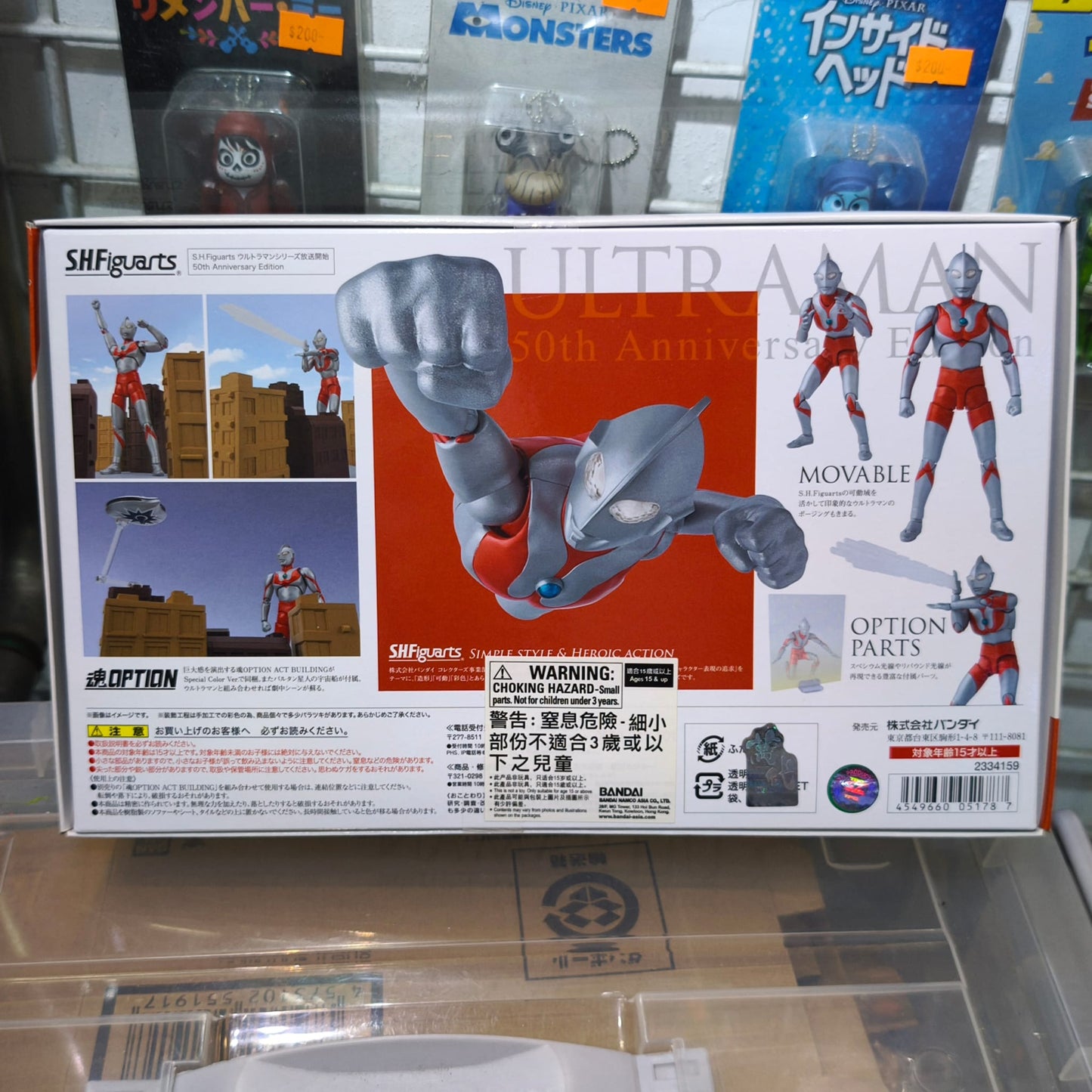 Back packaging of the S.H.Figuarts Ultraman figure, showing multiple preview action shots of the posable hero alongside included option parts like diorama miniature buildings and a flying saucer.
