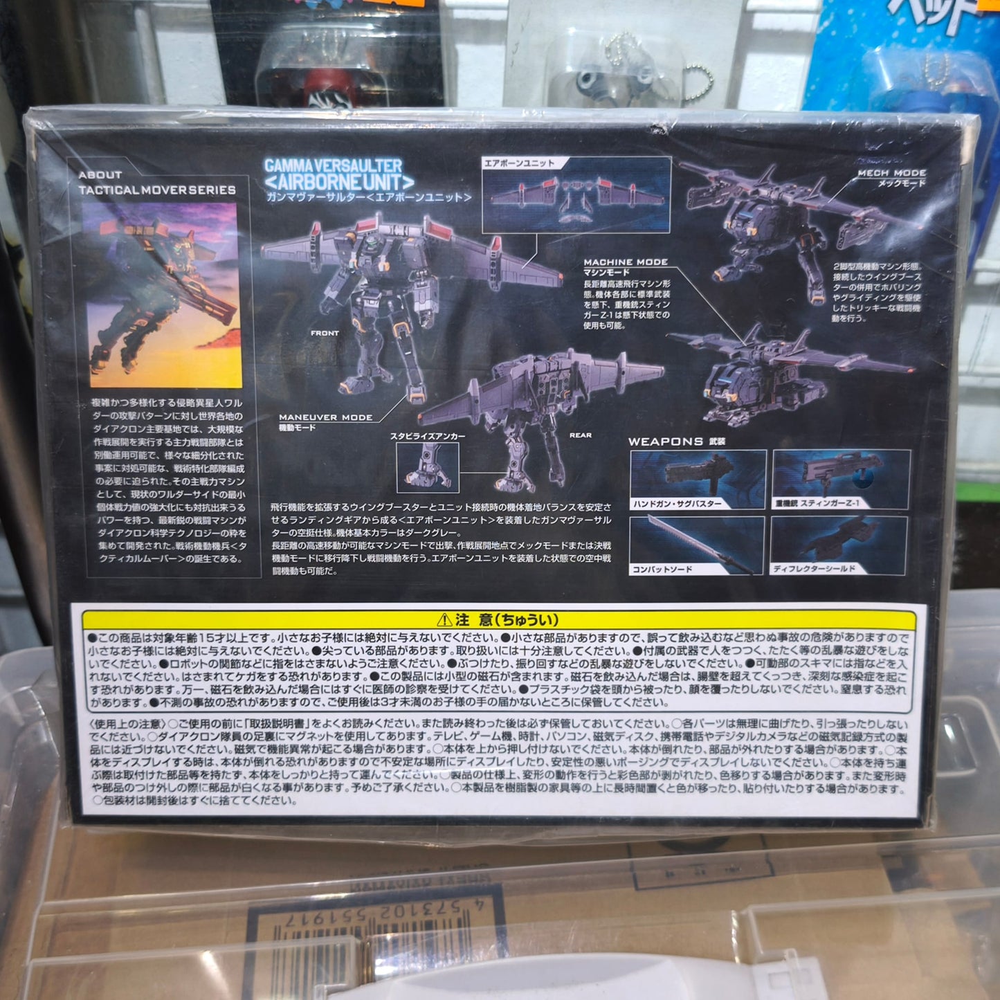 Back panel of the Gamma Versaulter box showing a detailed breakdown of its Maneuver, Machine, and Mech mode transformations alongside specialized weaponry attachments like the combat sword.