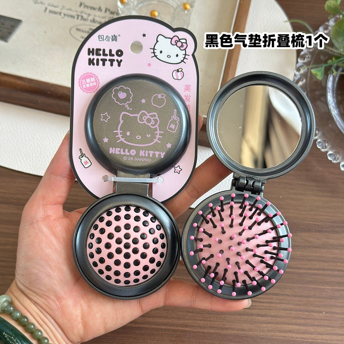 Black Hello Kitty folding air-cushion comb with mirror open on official Sanrio packaging card