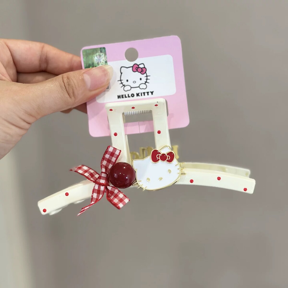 Close-up of the licensed Hello Kitty polka dot bar claw clip with red gingham bow and cherry accent