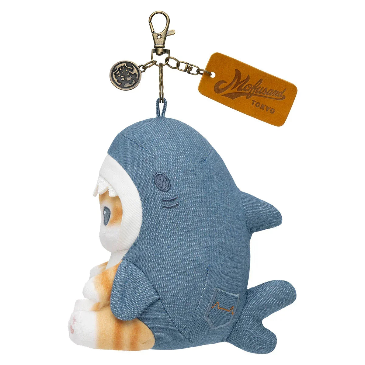 Side view of a Mofusand orange and white cat plush keychain in a blue denim shark costume