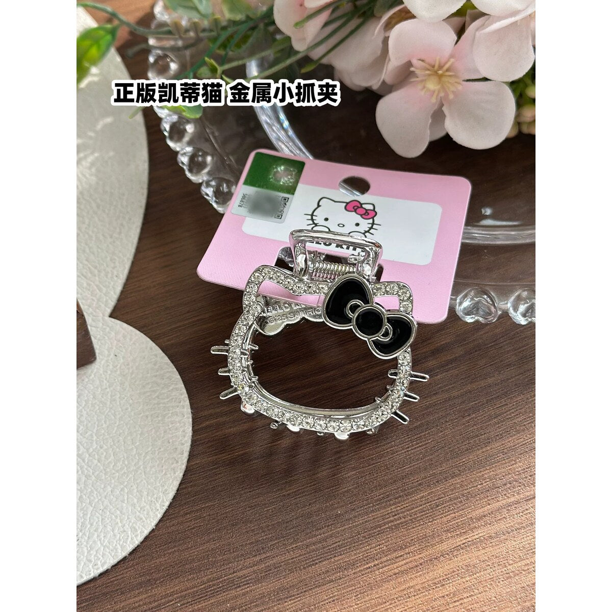 Hello Kitty rhinestone metal claw clip with black bow held in hand to show size