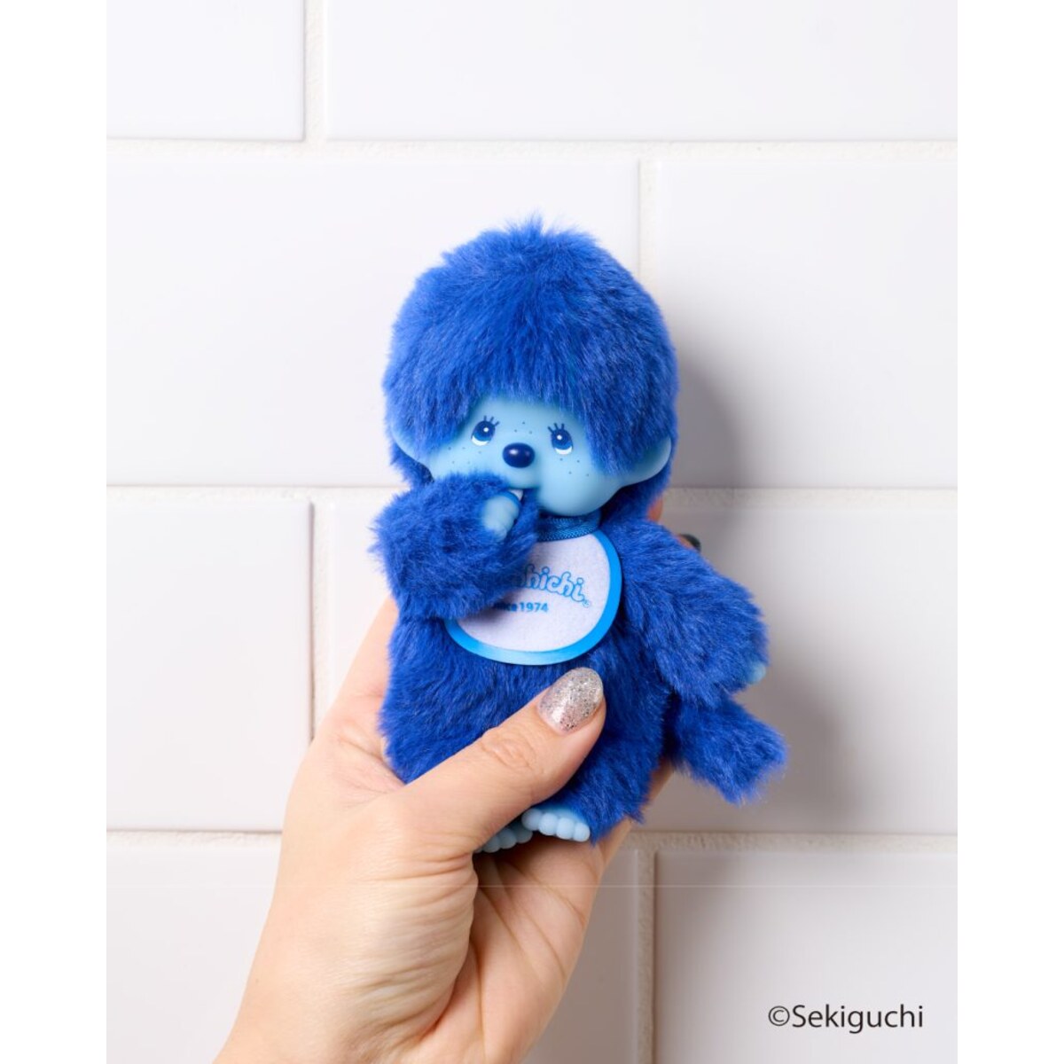 Blue macaron Monchhichi Colorful Fantasy plush keychain held in one hand to show its size