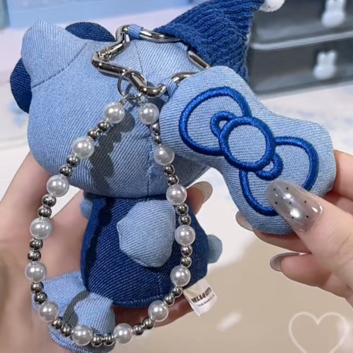 Back view of Hello Kitty denim series plush charm in blue denim with pearl bead chain and brand tag