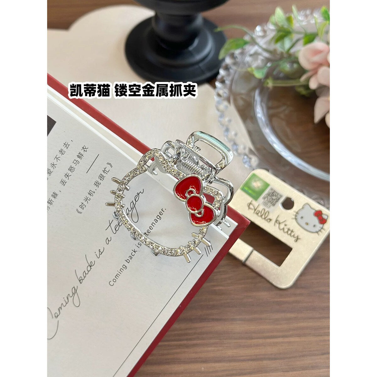 Hello Kitty rhinestone claw clip with red bow worn on a low bun hairstyle