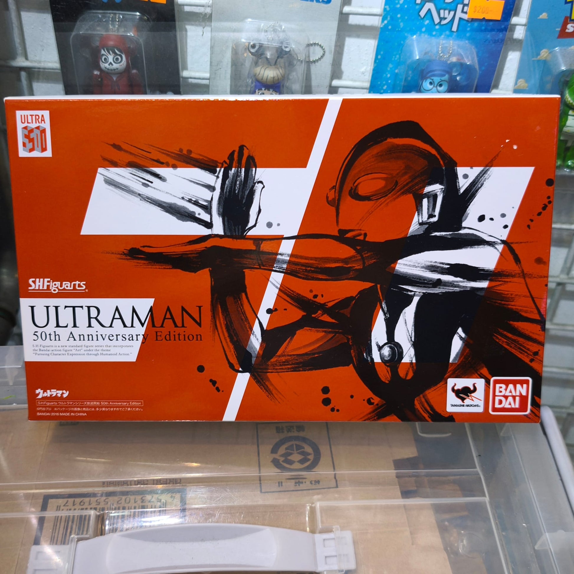 Front panel of the S.H.Figuarts Ultraman 50th Anniversary Edition box, featuring striking orange, black, and white ink-brush style artwork of Ultraman crossing his arms for his signature attack.