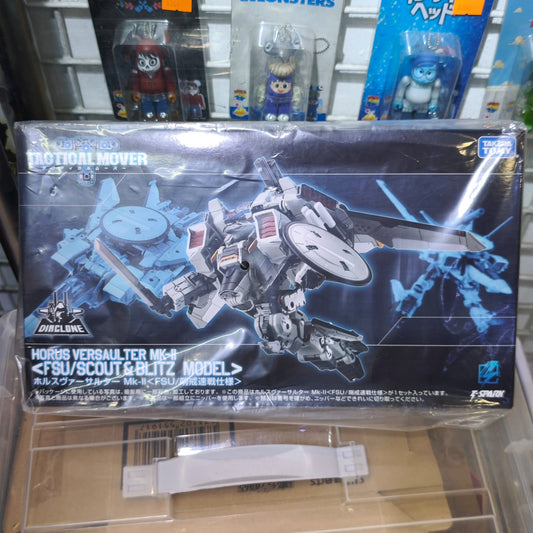 Front panel of the Takara Tomy Diaclone TM-32 packaging box, highlighting a dynamic action illustration of the white and grey Horus Versaulter Mk-II mecha diving forward with a combat sword and radome shield.
