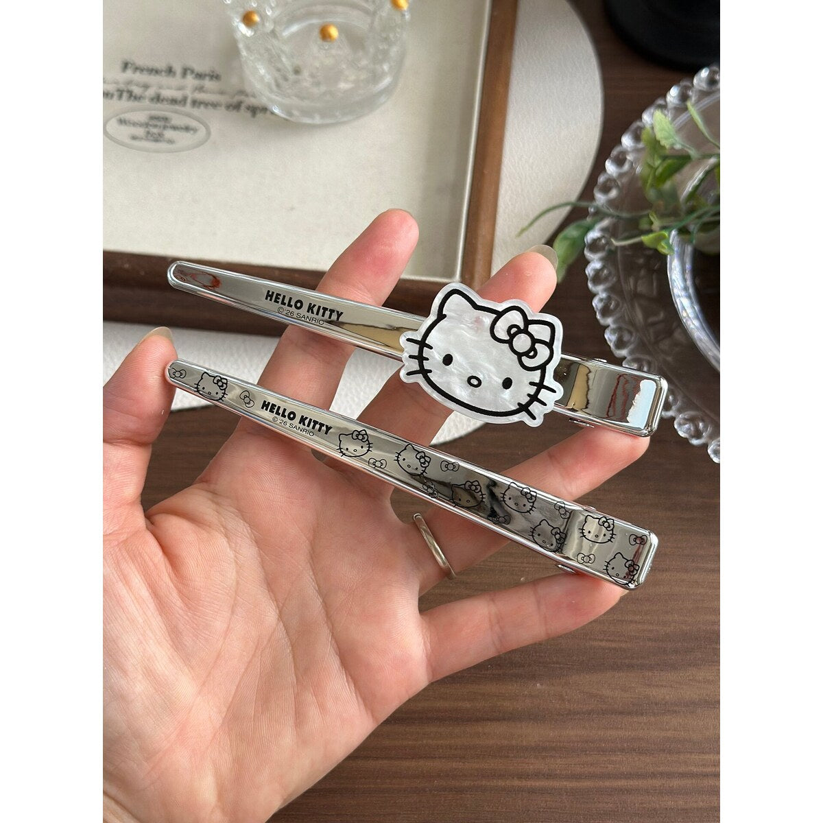 Hello Kitty extra large silver glitter bar clip held in hand next to the Hello Kitty anti-counterfeit card