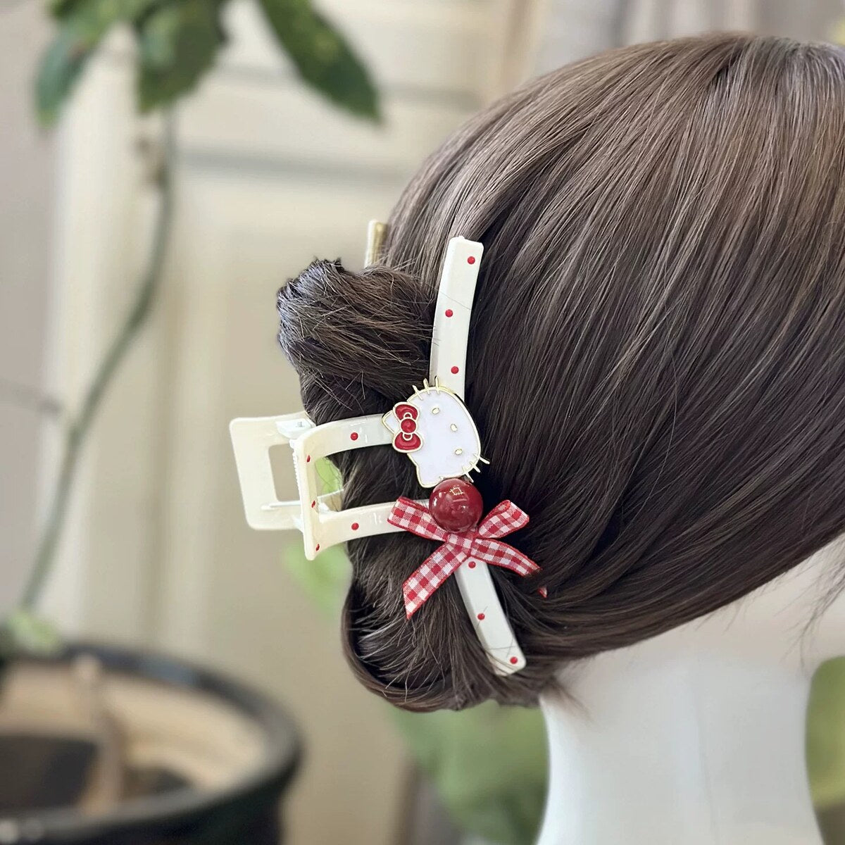Hello Kitty polka dot claw clip holding a low bun hairstyle